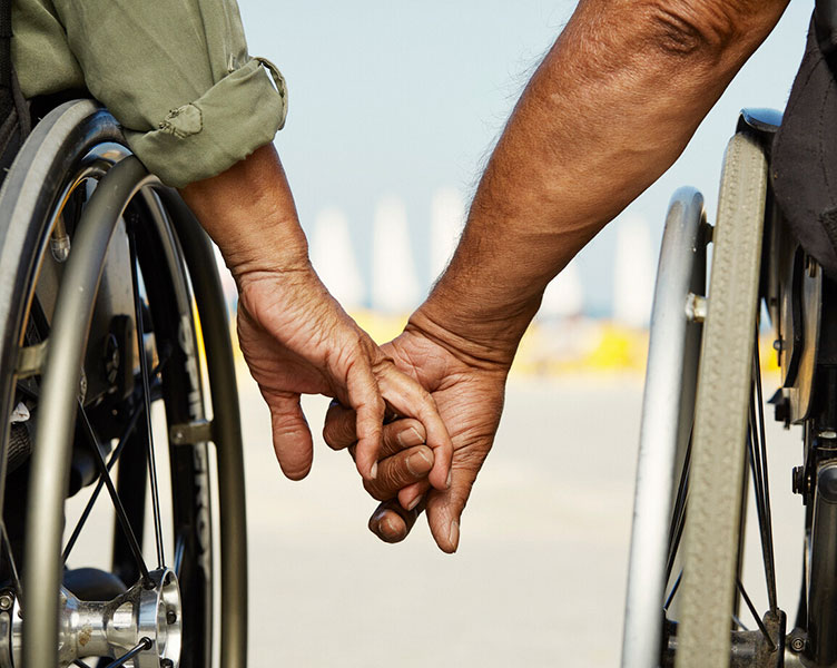 picture of 2 persons in wheelchairs holding hands