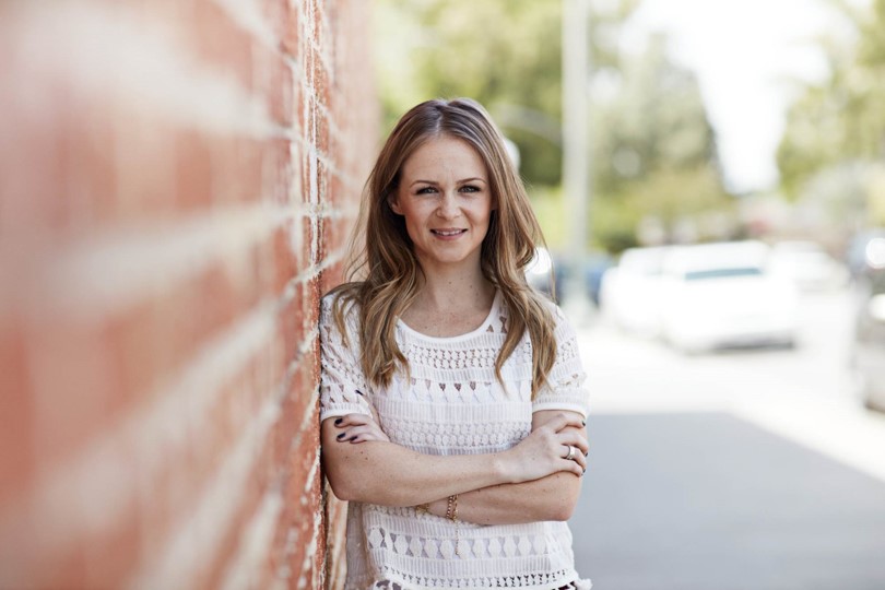 picture of a female Coloplast user standing close to a wall