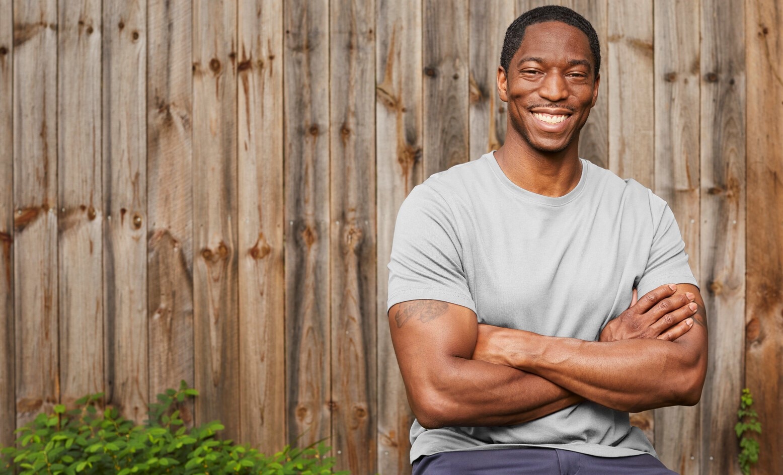 Brian smiling, standing in front of a fence